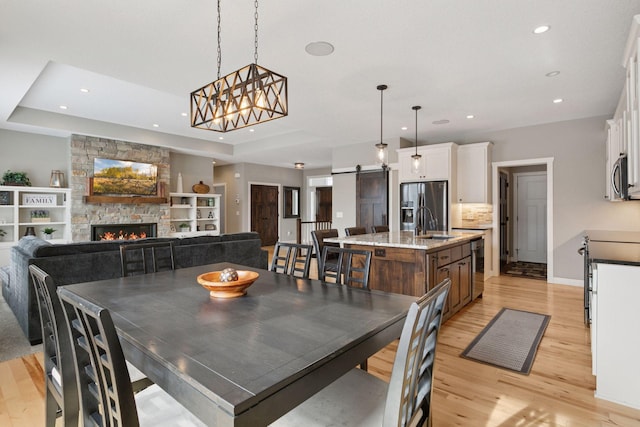 12770 196th Ave NW, Elk River, MN 55330 - dining area featuring recessed lighting, light wood-type flooring, a barn door, a stone fireplace, and beverage cooler