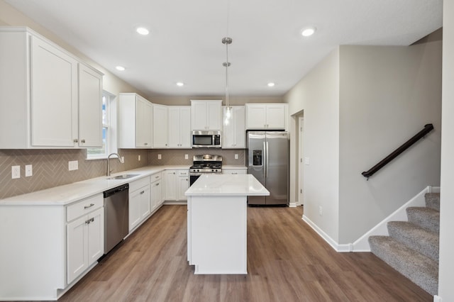 kitchen featuring a center island, pendant lighting, sink, appliances with stainless steel finishes, and white cabinets