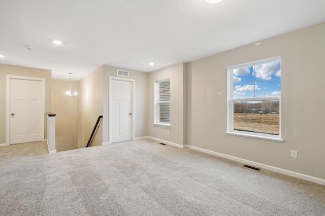 carpeted spare room with a chandelier