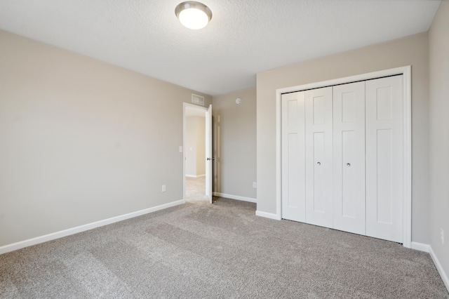 unfurnished bedroom featuring carpet, a closet, and a textured ceiling