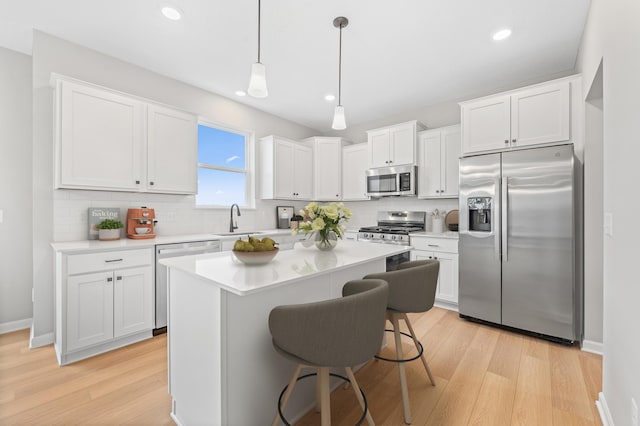 kitchen featuring a sink, appliances with stainless steel finishes, white cabinets, and light countertops