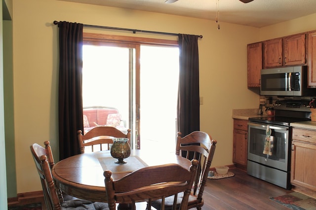 dining space featuring ceiling fan, plenty of natural light, dark wood finished floors, and baseboards