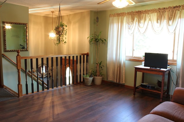 living area featuring dark wood-style floors, a ceiling fan, an upstairs landing, and baseboards