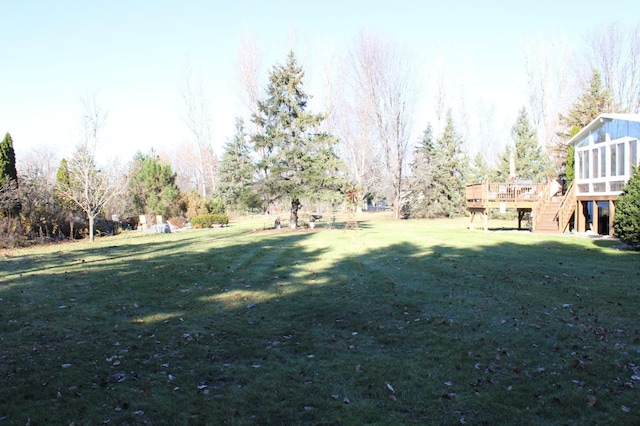 view of yard featuring a sunroom, stairs, and a wooden deck