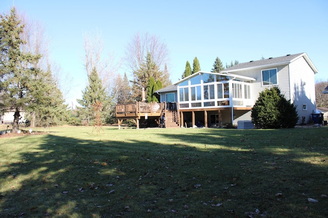 rear view of house with a sunroom, a lawn, a deck, and stairs