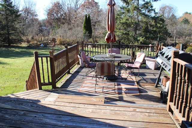 wooden terrace with outdoor dining area and a lawn