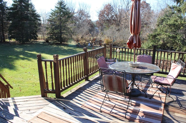 wooden deck featuring outdoor dining space and a lawn