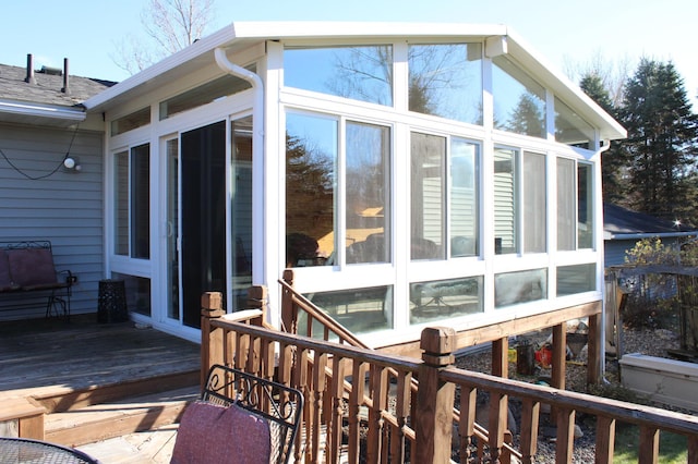 view of home's exterior with a sunroom, roof with shingles, and a wooden deck