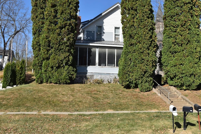 view of side of property with a sunroom and a yard