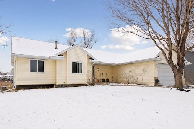 snow covered back of property featuring a garage