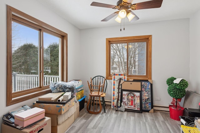 interior space with ceiling fan, a healthy amount of sunlight, light hardwood / wood-style flooring, and a baseboard radiator