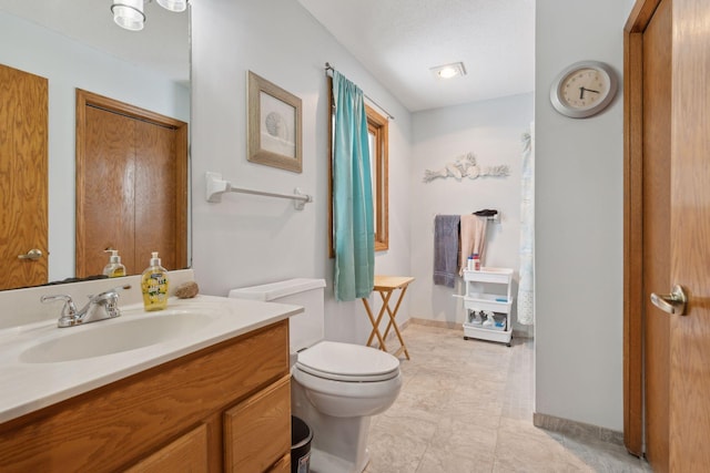 bathroom with a textured ceiling, toilet, and vanity