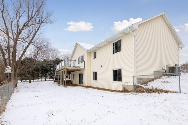 snow covered house with central AC unit and a deck