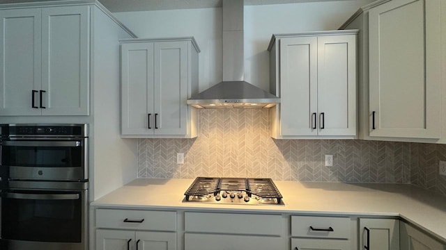 kitchen featuring wall chimney exhaust hood, appliances with stainless steel finishes, and tasteful backsplash