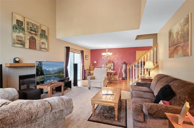 living room featuring a tiled fireplace, light colored carpet, and a notable chandelier