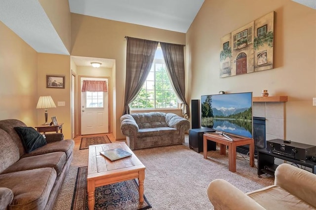 living room featuring carpet flooring, lofted ceiling, and a tile fireplace