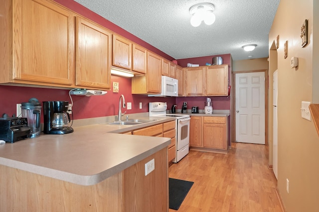 kitchen with sink, kitchen peninsula, a textured ceiling, white appliances, and light hardwood / wood-style flooring