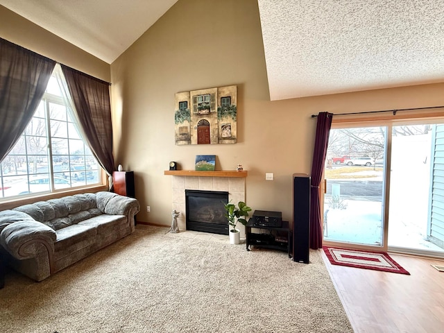 carpeted living area with a tile fireplace, high vaulted ceiling, and a textured ceiling