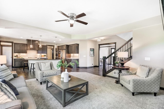 living room with dark hardwood / wood-style flooring, ceiling fan, and sink