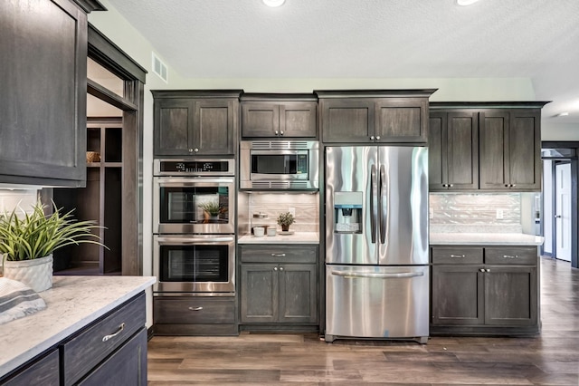 kitchen with dark hardwood / wood-style flooring, dark brown cabinets, and appliances with stainless steel finishes