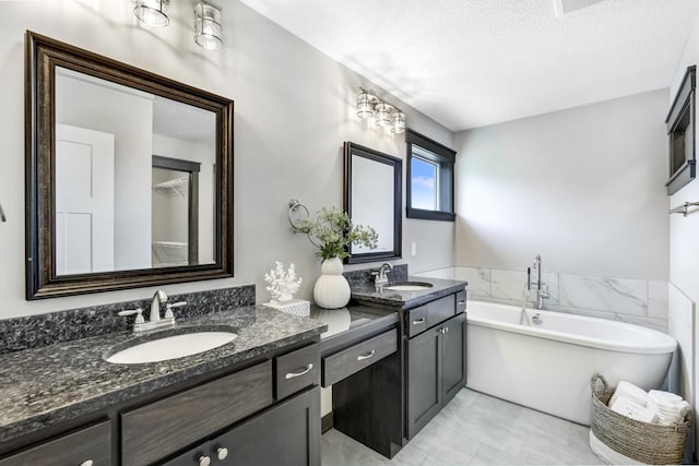 bathroom featuring vanity, a bath, and a textured ceiling