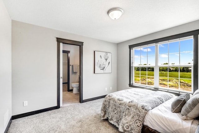 carpeted bedroom featuring a textured ceiling and ensuite bath