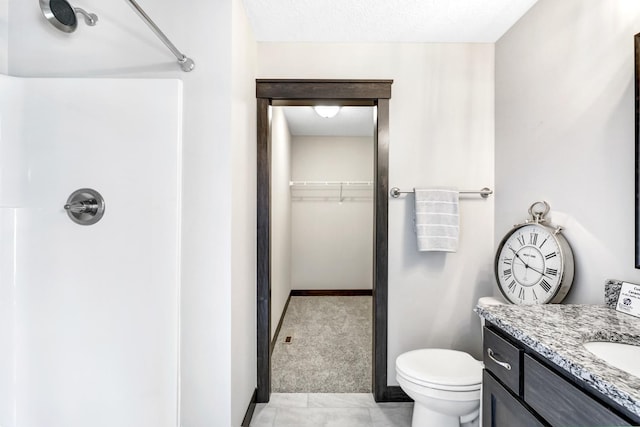 bathroom featuring a shower, a textured ceiling, vanity, and toilet