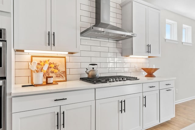 kitchen with white cabinetry, decorative backsplash, wall chimney range hood, and stainless steel gas cooktop