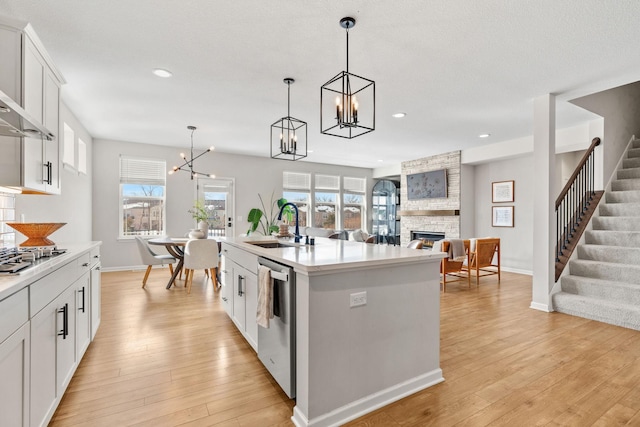 kitchen with a notable chandelier, a fireplace, appliances with stainless steel finishes, and a sink