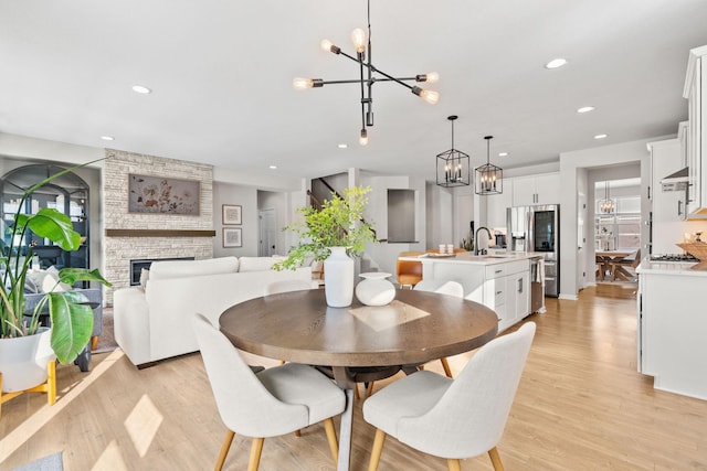 dining area with recessed lighting, a notable chandelier, light wood-style flooring, and a fireplace