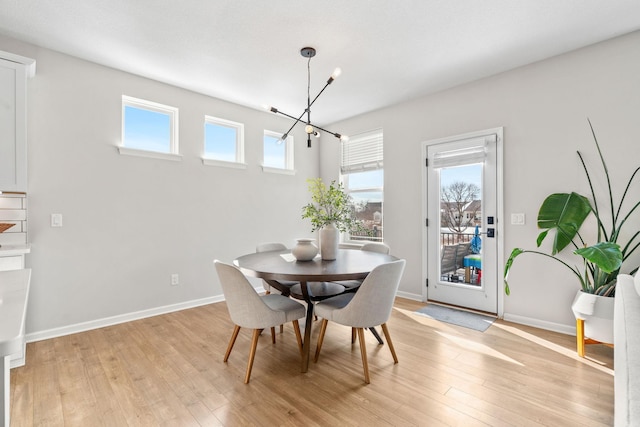 dining room with baseboards, a notable chandelier, and light wood-style flooring