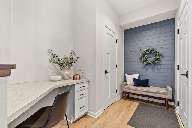 office area with wooden walls, built in study area, light wood-type flooring, and baseboards