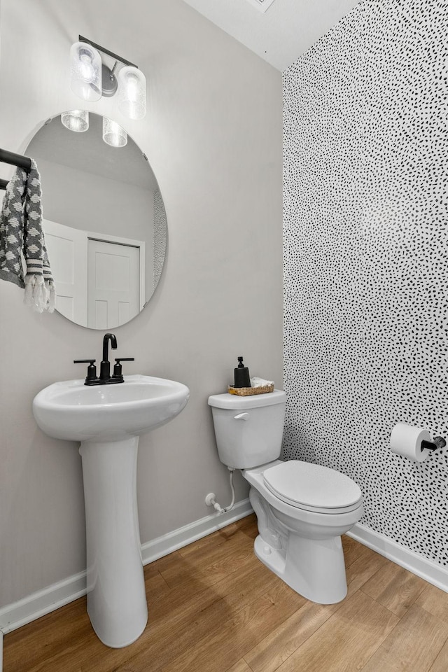 bathroom with baseboards, toilet, and wood finished floors