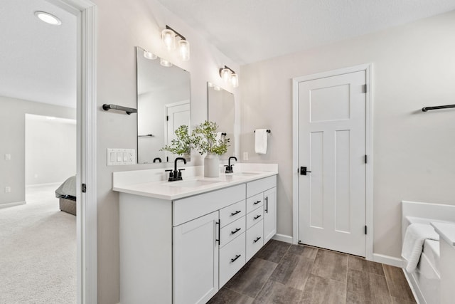 full bath featuring a sink, ensuite bath, wood finished floors, and double vanity