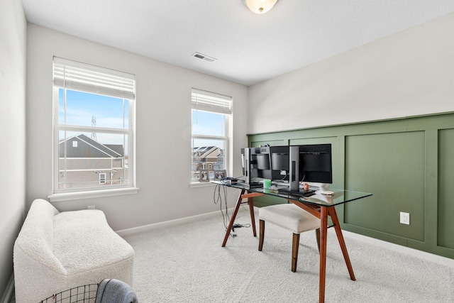 carpeted office space featuring visible vents, baseboards, and a decorative wall