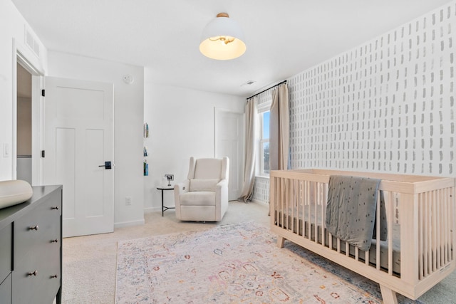 carpeted bedroom with a nursery area, visible vents, and baseboards