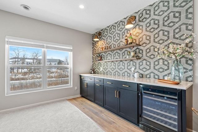 bar with baseboards, beverage cooler, recessed lighting, light wood-style flooring, and a bar