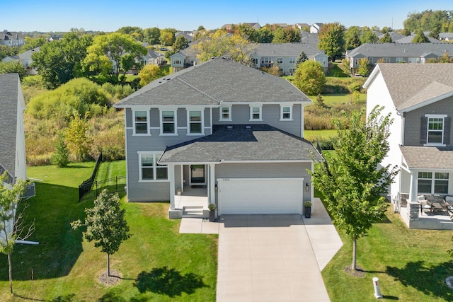 view of front of property with concrete driveway, a garage, a residential view, and a front lawn