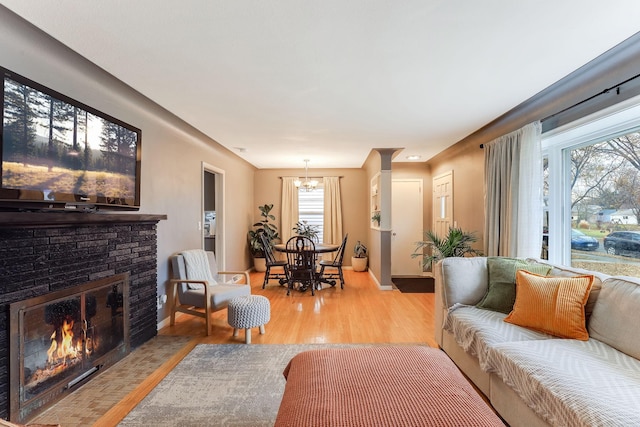 living room featuring a notable chandelier, a fireplace, and light hardwood / wood-style flooring