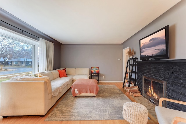 living room with light wood-type flooring and a brick fireplace