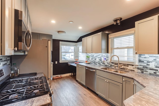 kitchen with tasteful backsplash, sink, stainless steel appliances, and light hardwood / wood-style flooring