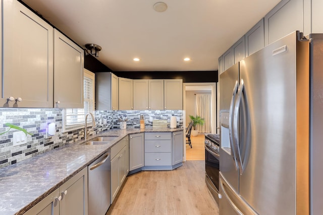 kitchen with sink, light wood-type flooring, stainless steel appliances, and stone counters