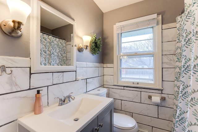 bathroom featuring vanity, tile walls, and toilet