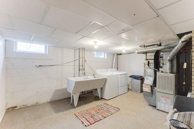 basement featuring washer and dryer, a drop ceiling, sink, and heating unit