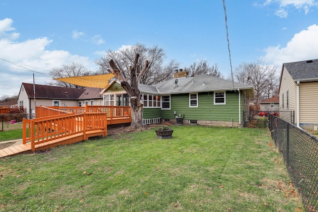 back of property with a wooden deck and a lawn