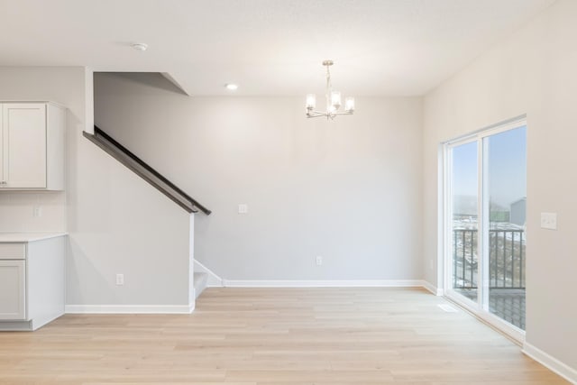 unfurnished room with light hardwood / wood-style floors and an inviting chandelier