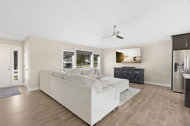 living area featuring a ceiling fan, light wood-style flooring, and baseboards