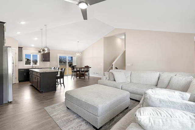 living area with visible vents, lofted ceiling, wood finished floors, stairs, and a chandelier