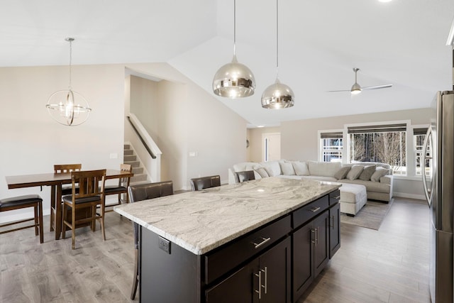 kitchen featuring light wood finished floors, vaulted ceiling, open floor plan, and freestanding refrigerator