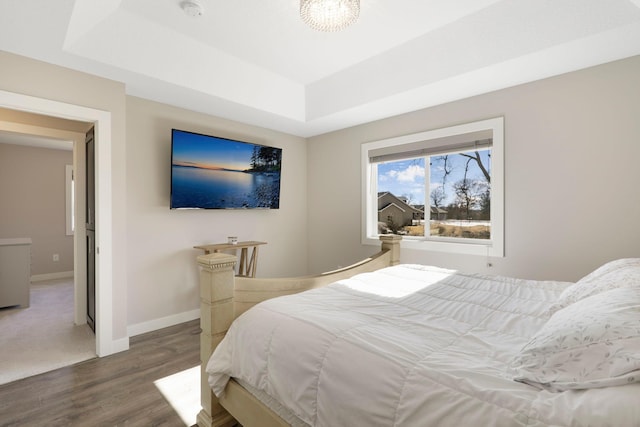 bedroom featuring a notable chandelier, baseboards, a raised ceiling, and wood finished floors